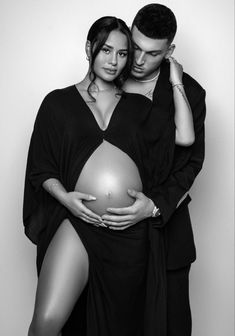 a man and woman are posing for a black and white photo with their pregnant belly