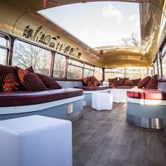 the inside of a bus with couches and pillows on it's side wall