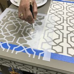 a person is painting on a table with blue tape