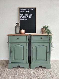 two green cupboards sitting next to each other in front of a chalkboard sign