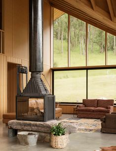 a living room with large windows and a wood burning stove in the middle of it