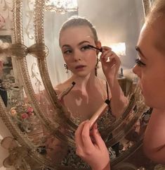 a woman is doing makeup in front of a mirror