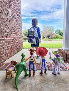 several toy figurines are lined up in front of a brick wall and door