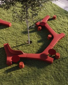 a red bench sitting on top of a lush green field next to a small tree