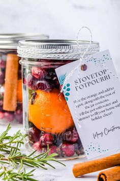 a jar filled with oranges, cranberries and cinnamon sticks next to an empty tag