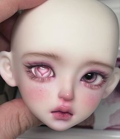 a close up of a doll's face with pink eyeliners and eyelashes