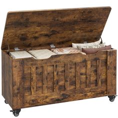 an old wooden trunk with some pillows and blankets on it's wheels, sitting against a white background