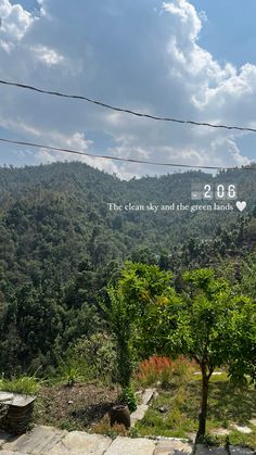 the words are written in white on top of trees and mountains with clouds above them