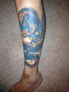 a person with a blue dragon tattoo on their leg and foot is shown from above