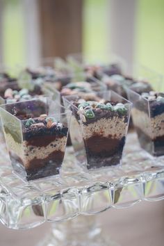 several desserts are arranged in small cups on a clear tray