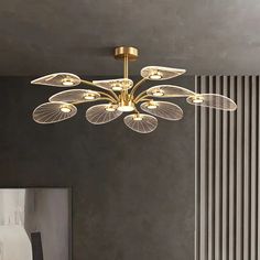 a modern style chandelier hanging from the ceiling in a room with grey walls