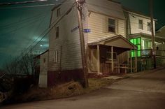 an old house is lit up at night with green light from the street lights on