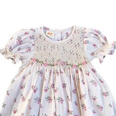 This lovely dress features a cream-colored fabric adorned with delicate pink and purple flowers. The smocked detailing adds a charming touch to the overall design, making it a perfect choice for a stylish and elegant look.  * 100% Cotton * 2 layers * Handmade * Tie at the back * Lightweight, soft cotton, comfortable * Hand wash or machine wash on a delicate setting We are based in Sydney, New South Wales, Australia. Within Australia, Standard shipping is $7 flat rate via AusPost. There is option Summer Floral Dress With Smocked Bodice And Puff Sleeves, Feminine Smocked Floral Dress For Garden Party, Cute Smocked Dress For Spring Garden Party, Feminine Floral Smocked Dress For Garden Party, Feminine Floral Print Smocked Dress For Garden Party, Pink Floral Dress With Smocked Back For Spring, Spring Floral Dress With Smocked Bodice For Garden Party, Floral Dress With Smocked Bodice For Spring Garden Party, Feminine Smocked Dress With Puff Sleeves And Floral Print