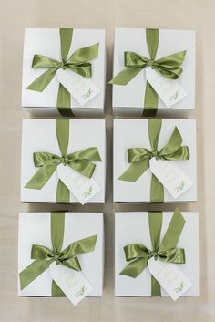 four white boxes with green ribbons tied around them