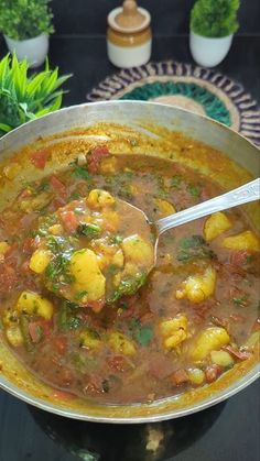 a large pot filled with stew and vegetables on top of a table next to plants