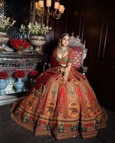 a woman in a red and gold dress sitting on a chair