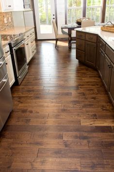 a kitchen with wood flooring and stainless steel appliances in the middle of the room