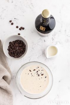 two bowls filled with milk and chocolate chips next to a bottle of booze on a marble surface