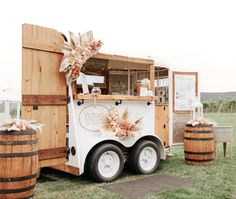 the food truck is decorated with flowers and ribbons on it's side, along with two wooden barrels