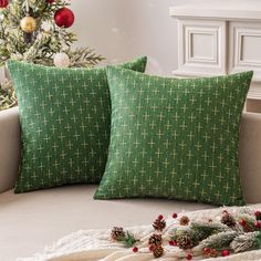 two green pillows sitting on top of a couch next to a christmas tree and decorations