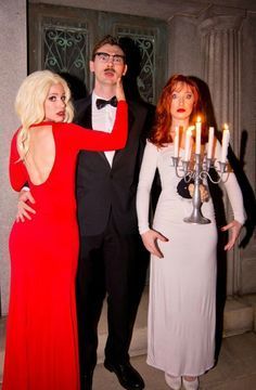 three people dressed up in formal wear posing for a photo with candles on their heads