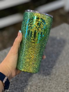 a hand holding a green glitter tumbler cup