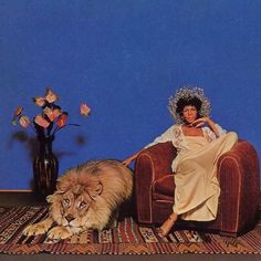 a woman sitting in a chair next to a lion and vase with flowers on it