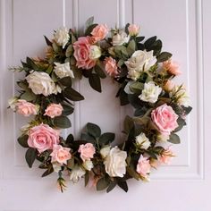 a wreath with pink and white flowers is hanging on the front door's wall