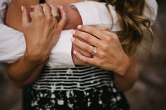 a man and woman holding each other close to one another with their hands on his chest