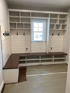 an empty room with white shelving and wooden benches