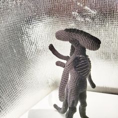 a crocheted stuffed animal standing on its hind legs in front of a window