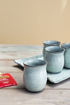 there are four cups on the table next to a packet of chips and a napkin