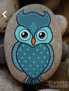 an owl painted on a rock next to some rocks