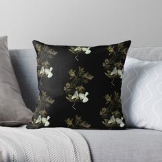 a black background with white flowers and leaves on the back of a couch throw pillow