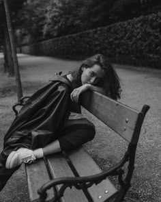 a woman sitting on top of a wooden bench