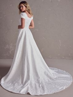 a woman in a white wedding dress is standing on a circular rug with her back to the camera