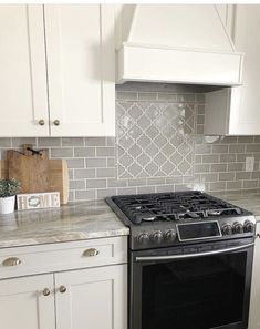 a stove top oven sitting inside of a kitchen next to white cabinets and counter tops