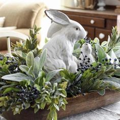 a white rabbit statue sitting on top of a wooden box filled with greenery