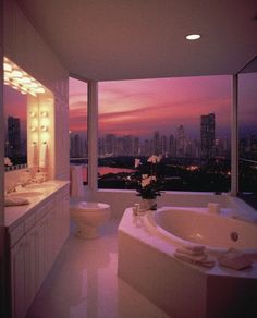 a bathroom with a large tub and two sinks in front of a window overlooking the city