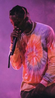 a man with dreadlocks on his head holding a microphone in front of a purple background