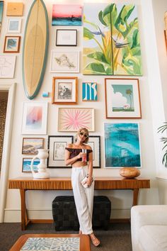 a woman standing in front of a wall full of pictures and surfboards on it