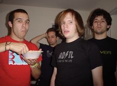 a group of young men standing next to each other holding food in front of their faces