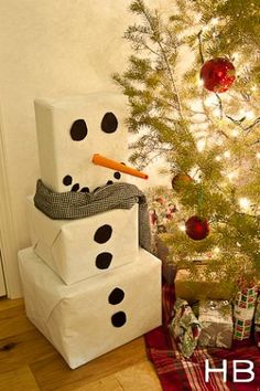 a snowman made out of boxes next to a christmas tree