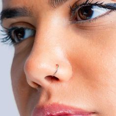 a woman's nose has a piercing on it and is looking at the camera