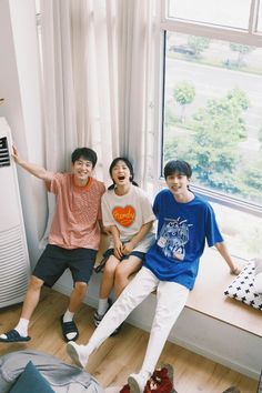 three boys sitting on a window sill in front of a heater and air conditioner