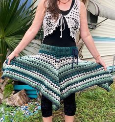 a woman standing in front of a camper with her hands on her hips wearing a green and white crocheted skirt