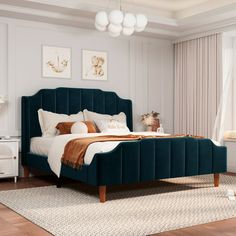 a bedroom with white walls and wooden floors, a bed in black velvet upholstered headboard