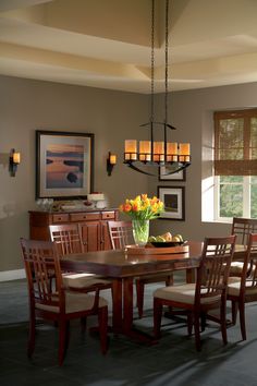 a dining room table with flowers in a vase on the top and chairs around it