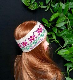 a headband with flowers on it sits next to a bush and leaves in front of a black background