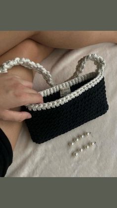 a woman's hand is holding a black and white purse with pearls on it